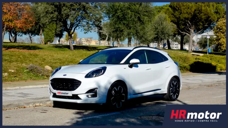 Coche Ford Puma con carrocería en blanco aparcado al lado de un parque.